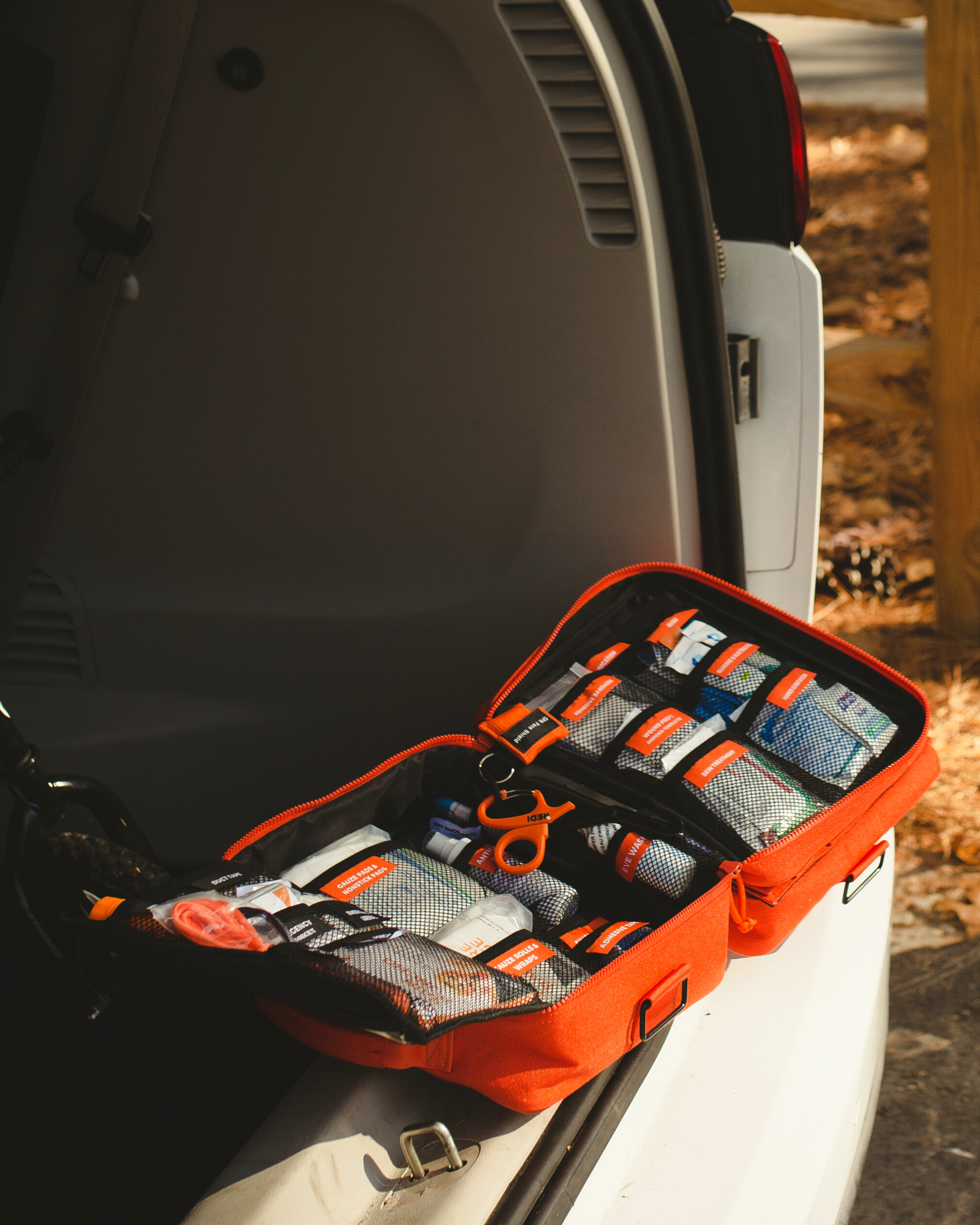 Roadie first aid kit opened up in the trunk of a car at the park.